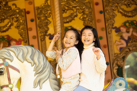 愉快的积极表现积极活力秋天两个小女孩在玩旋转木马背景