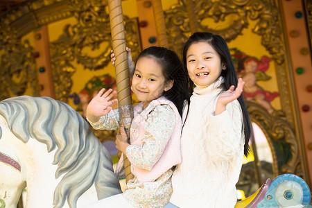 郊游健康的玩耍两个小女孩在玩旋转木马图片