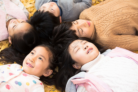 摄影户外落叶可爱的男孩女孩躺在地上图片