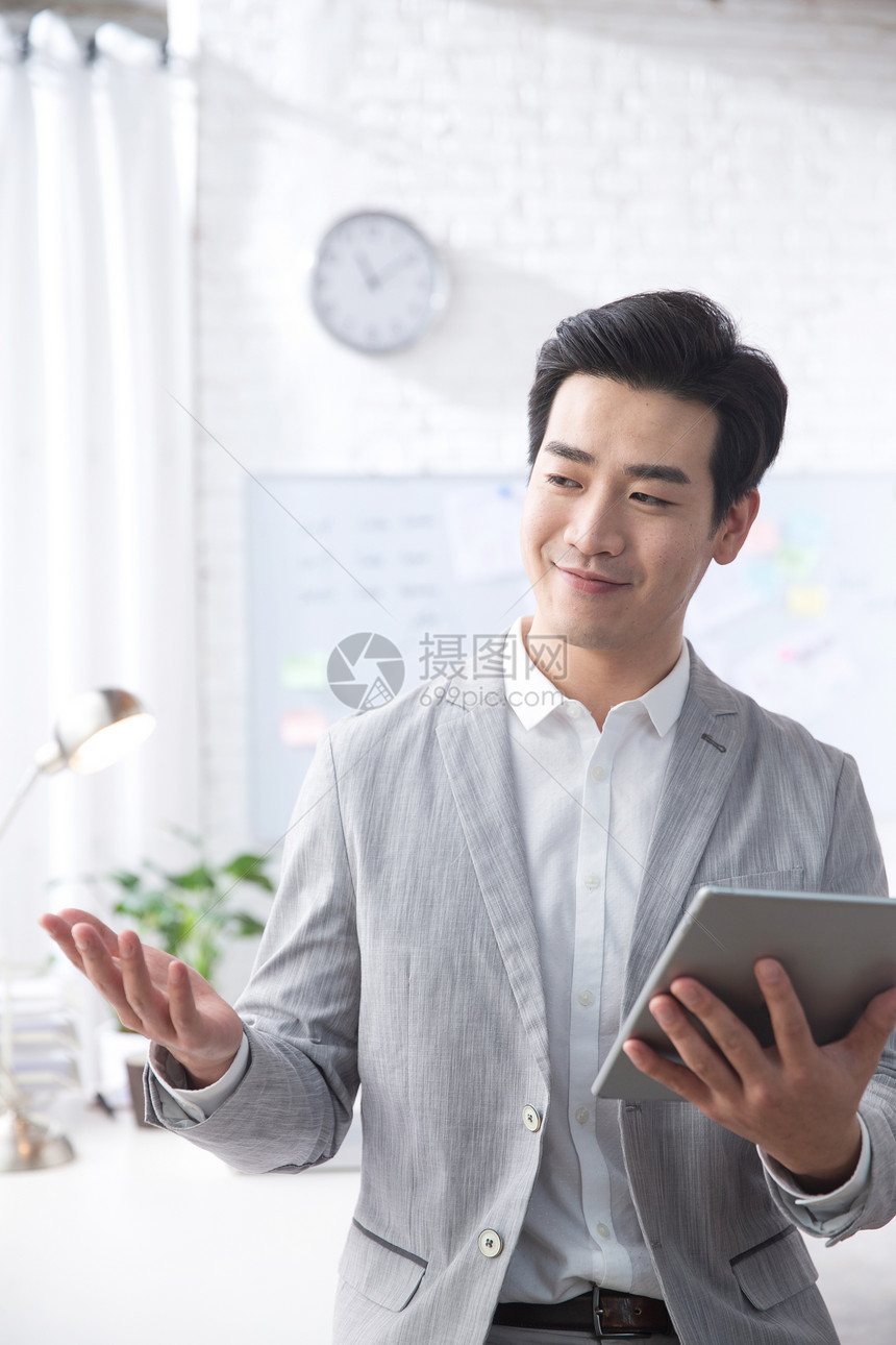 成年人垂直构图公司企业青年商务男人拿着平板电脑办公图片