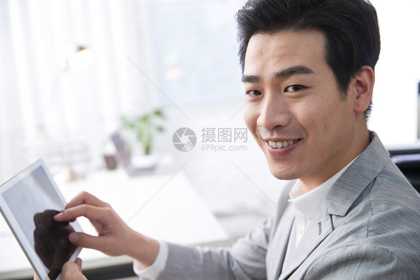 亚洲彩色图片水平构图青年商务男人拿着平板电脑办公图片