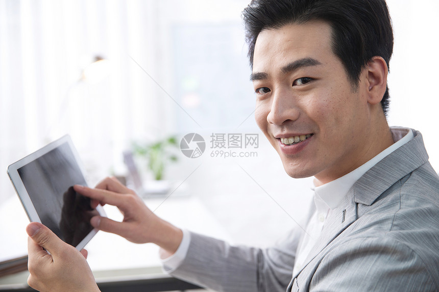 新创企业青年商务男人拿着平板电脑办公图片