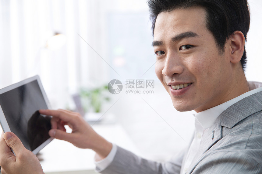 着装得体亚洲人青年商务男人拿着平板电脑办公图片