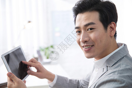 东亚办公区轻松办公青年商务男人拿着平板电脑办公图片