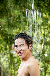 微笑的脸年轻男人在户外淋浴洗头图片