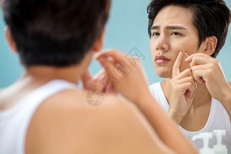 身体关注彩色图片家居服年轻男人对着镜子挤痘背景图片