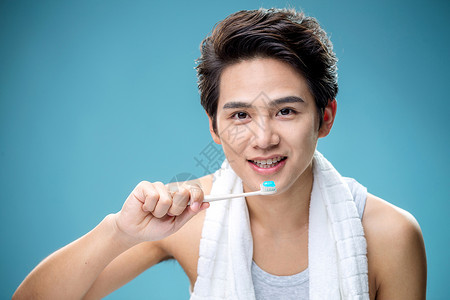 挂着的毛巾牙刷头和肩膀欢乐年轻男人在刷牙背景
