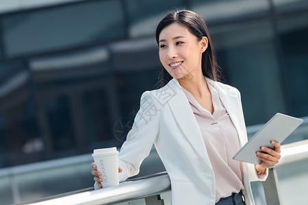 户外平板金融区拿着平板电站在户外的商务女士背景