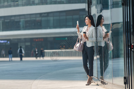 互联网大楼图图片青年商务女人站在户外看手机背景