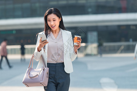 视频短信精力不看镜头女商人青年商务女人边走边看手机背景