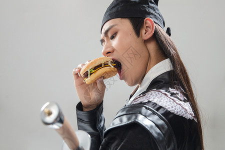 特色服装武侠东亚吃汉堡的青年男人图片