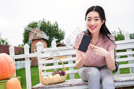 双指水平移动美丽的水平构图享乐青年女人坐在户外展示手机背景