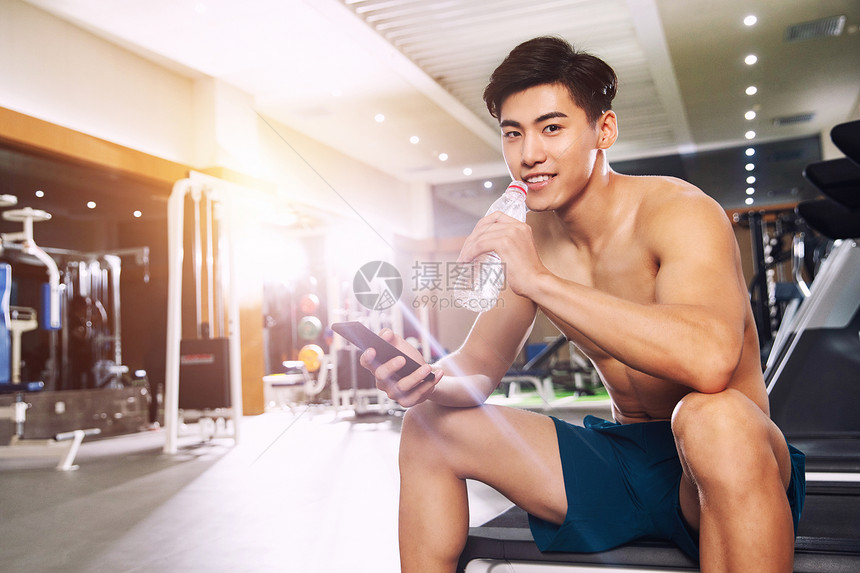 欢乐青年男人在健身房里喝水图片