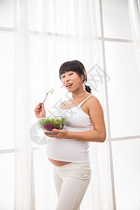 怀孕新妈妈健康的幸福的孕妇吃蔬菜沙拉背景