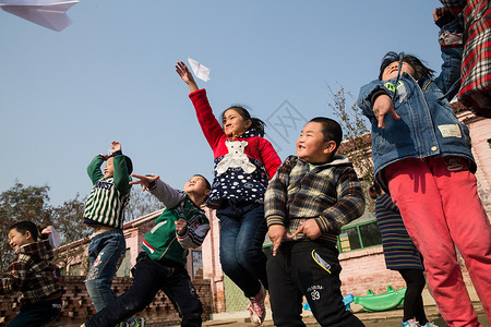 放纸飞机男孩玩耍梦想嬉戏的乡村小学生在学校放纸飞机背景