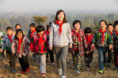 为梦想奔跑人人关爱小学乡村女教师和学生在玩耍背景