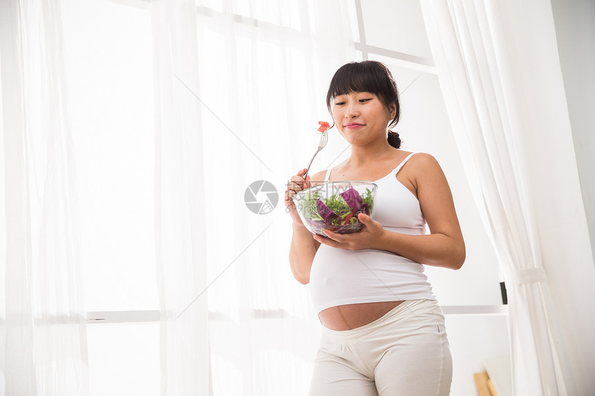 希望20多岁新生活幸福的孕妇吃蔬菜沙拉图片