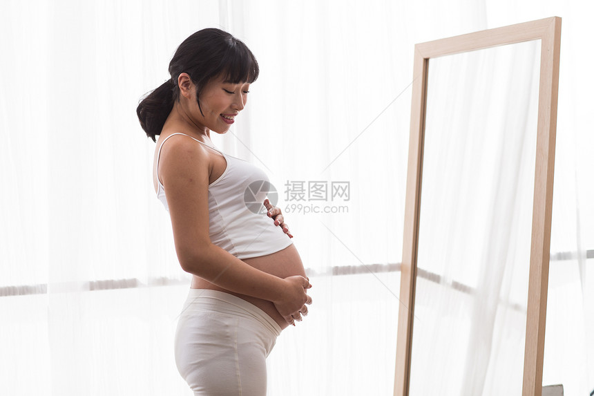 青年女人轻松期待孕妇照镜子图片