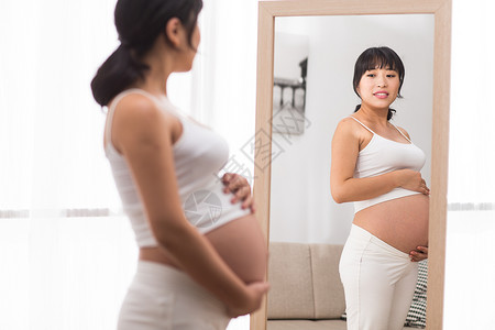 腹部触摸微笑孕妇照镜子图片