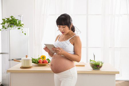 怀孕新妈妈爱沟通起居室孕妇看平板电脑背景