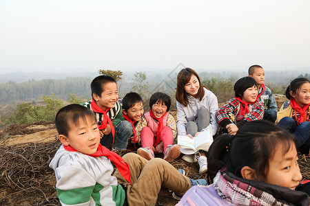 坐着读书孩子彩色图片坐着乡村教师和小学生在户外学习背景