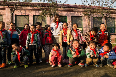 站着25岁到29岁幸福乡村教师和小学生在学校里图片