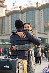 情侣在户外拥抱中年男人旅行箱亲密青年情侣在火车站背景