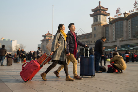 男女手牵手旅行的人水平构图城市风光青年男女在站前广场背景