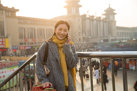 春节旅行者旅行箱青年女人在站前广场图片