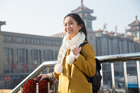 车站旅行的人拿着青年女人在站前广场图片