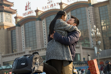 情侣在户外拥抱春运旅行箱户外青年情侣在火车站背景