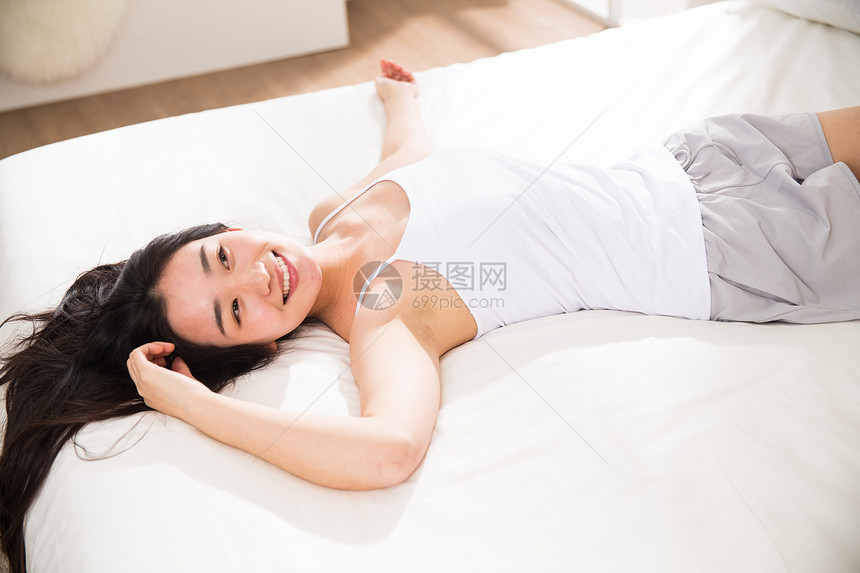 惬意早晨青年女人在卧室的床上图片