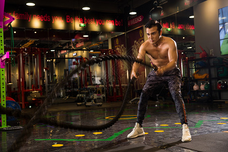 体能器材青年男人在健身房里健身摔绳索背景
