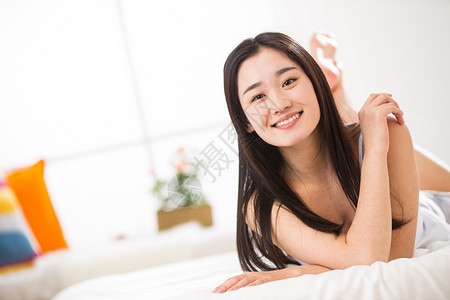 起床微笑趴着青年女人趴在床上图片