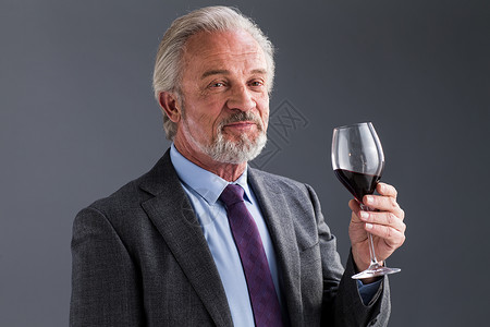 着装得体权威商务老年男人品红酒图片
