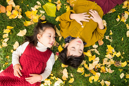 躺在叶子上男孩可爱的儿童在户外躺在银杏叶上背景