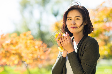 玩耍白昼树叶青年女人在户外图片