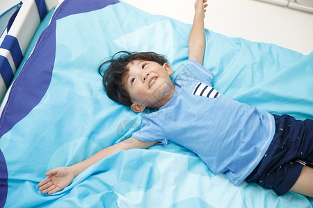 床上用品蓝色住宅房间可爱的小男孩在床上玩耍图片