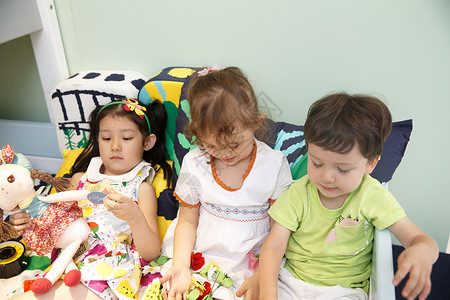 女孩三个人男孩欢乐的儿童在床上玩耍图片