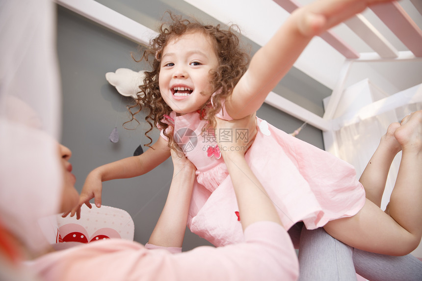 多种族家放松可爱的小女孩和妈妈在卧室玩耍图片