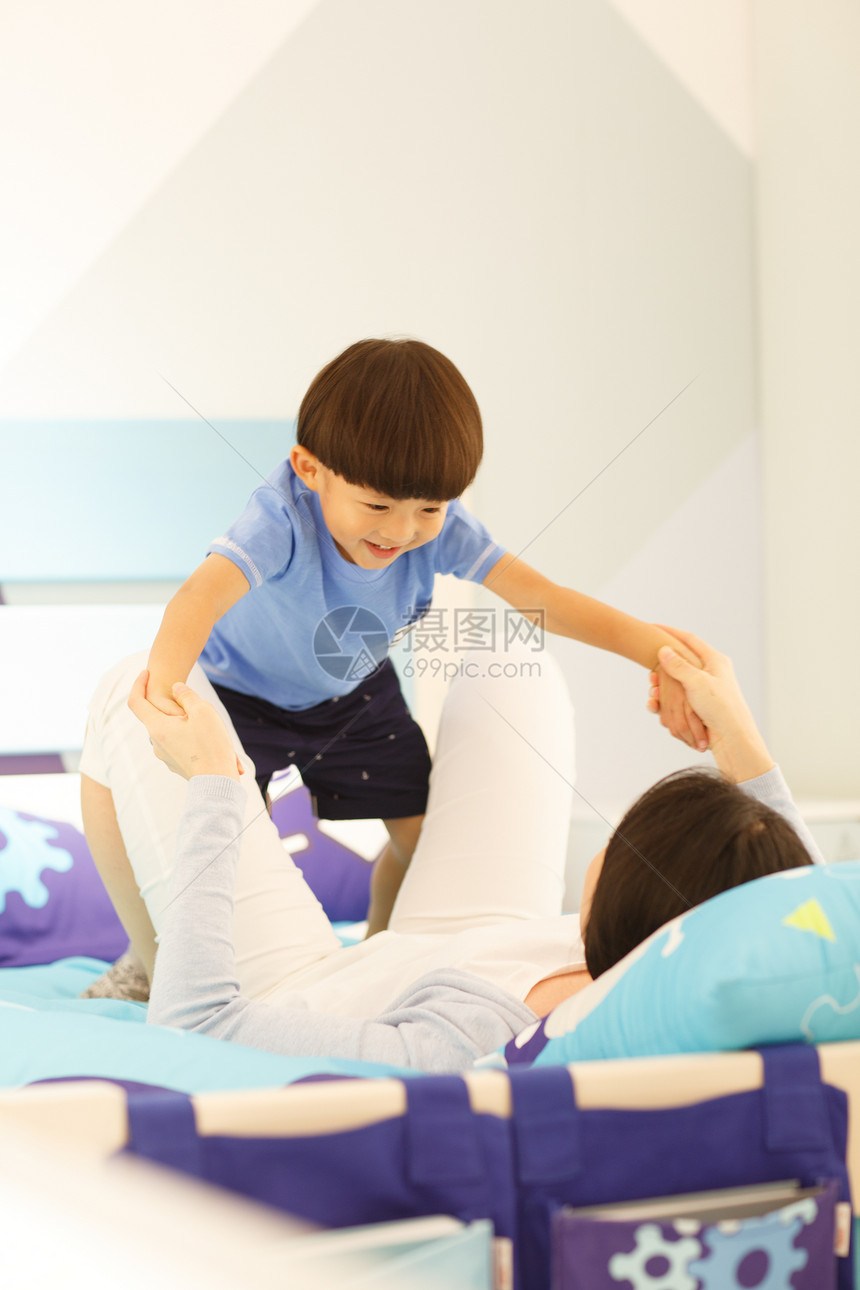 生长放松床上用品可爱的小男孩和妈妈在卧室玩耍图片