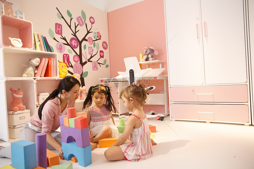学龄前儿童娱乐室儿童房青年女人和两个女孩在卧室玩耍图片