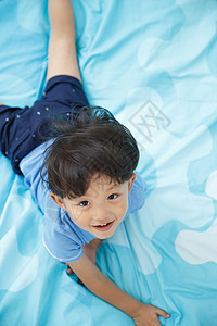 纯洁休闲装天真可爱的小男孩在床上玩耍图片