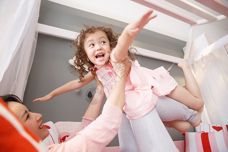 中年女人卷发彩色图片可爱的小女孩和妈妈在卧室玩耍高清图片