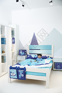 蓝色可爱闹钟垂直构图学龄前儿童活力可爱的小男孩在床上玩耍背景