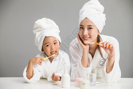 时尚母亲满意微笑穿着浴袍的母女刷牙背景