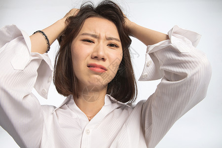 手插入头发仅一个青年女人正面视角抓面部表情痛苦的青年女人背景