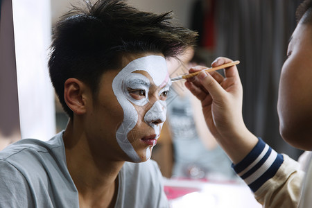 画笔元素化妆师在为京剧演员化妆背景