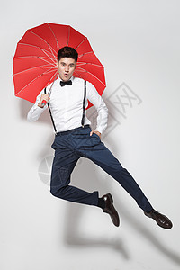 青年男人拿着心形红雨伞跳跃高清图片