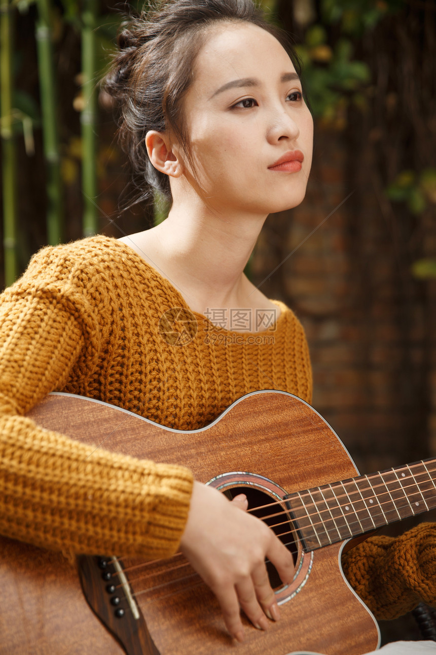 庭院毛衣年轻女人弹吉他图片